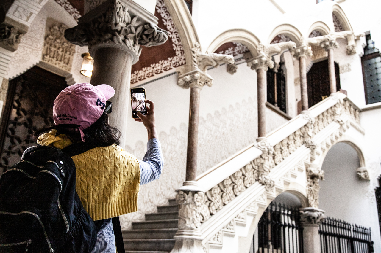 Guest on architecture tour taking photo of an ornate staircase